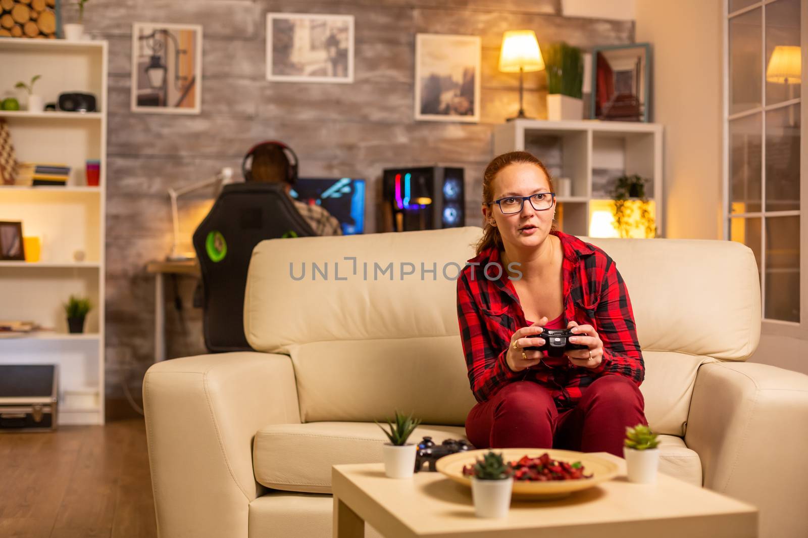 Woman gamer playing video games on the console in the living room late at night