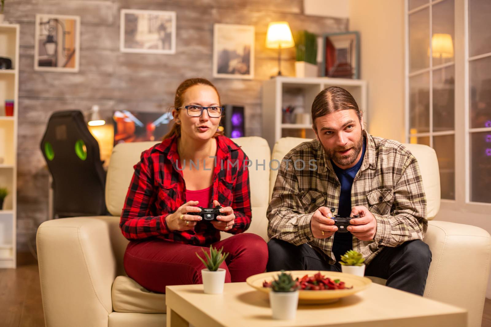 Gamers couple playing video games on the TV with wireless controllers in hands.