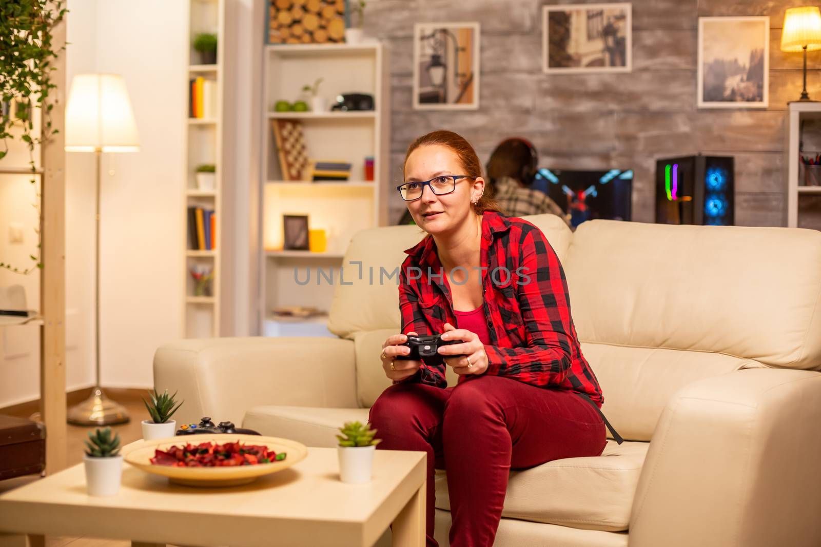 Woman gamer playing video games on the console in the living room late at night