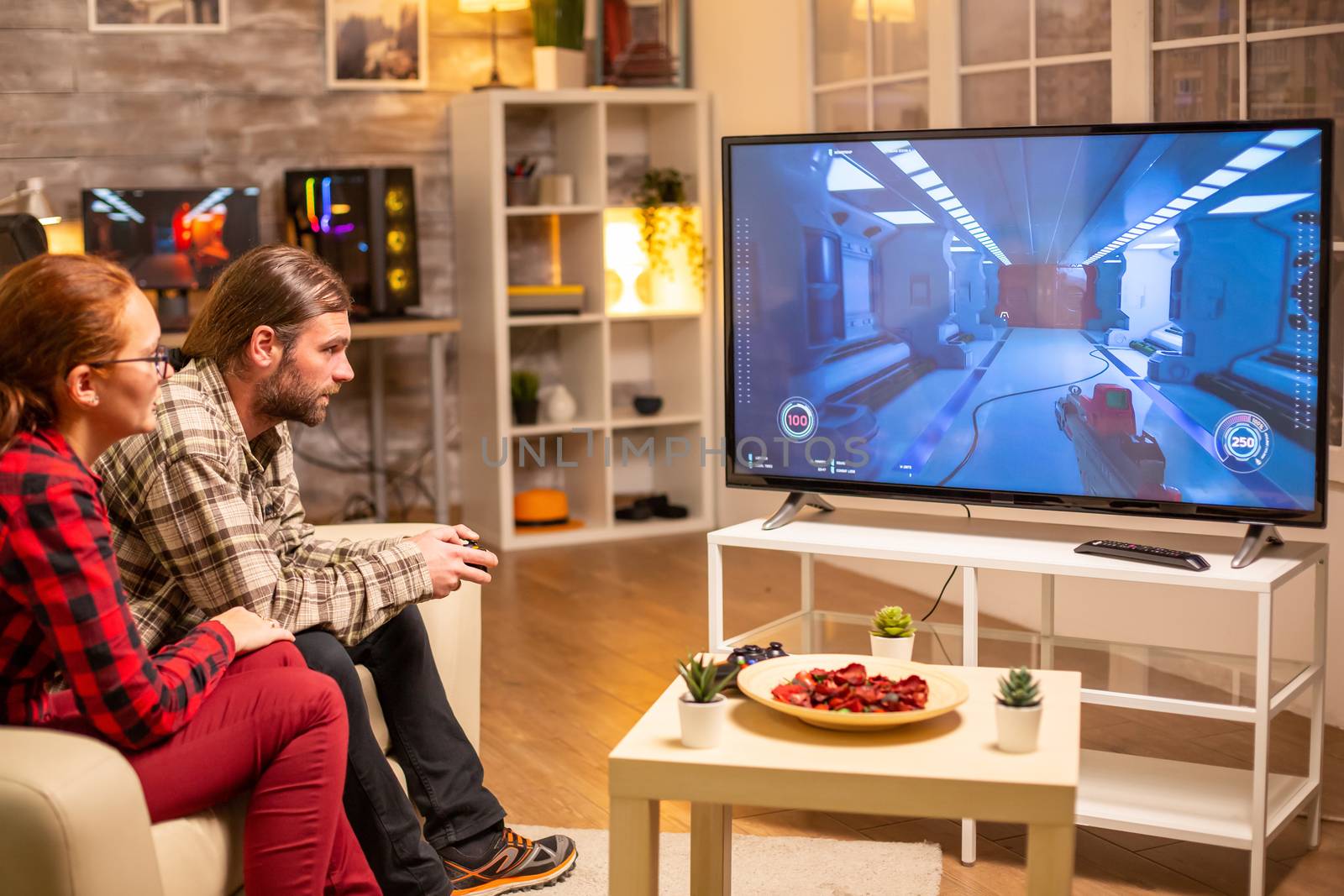 Couple playing video games on big screen TV in the living room late at night.