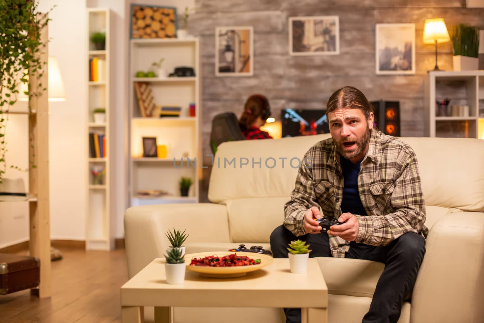 Angry and frustrated man video game player on the sofa late at night in the living room