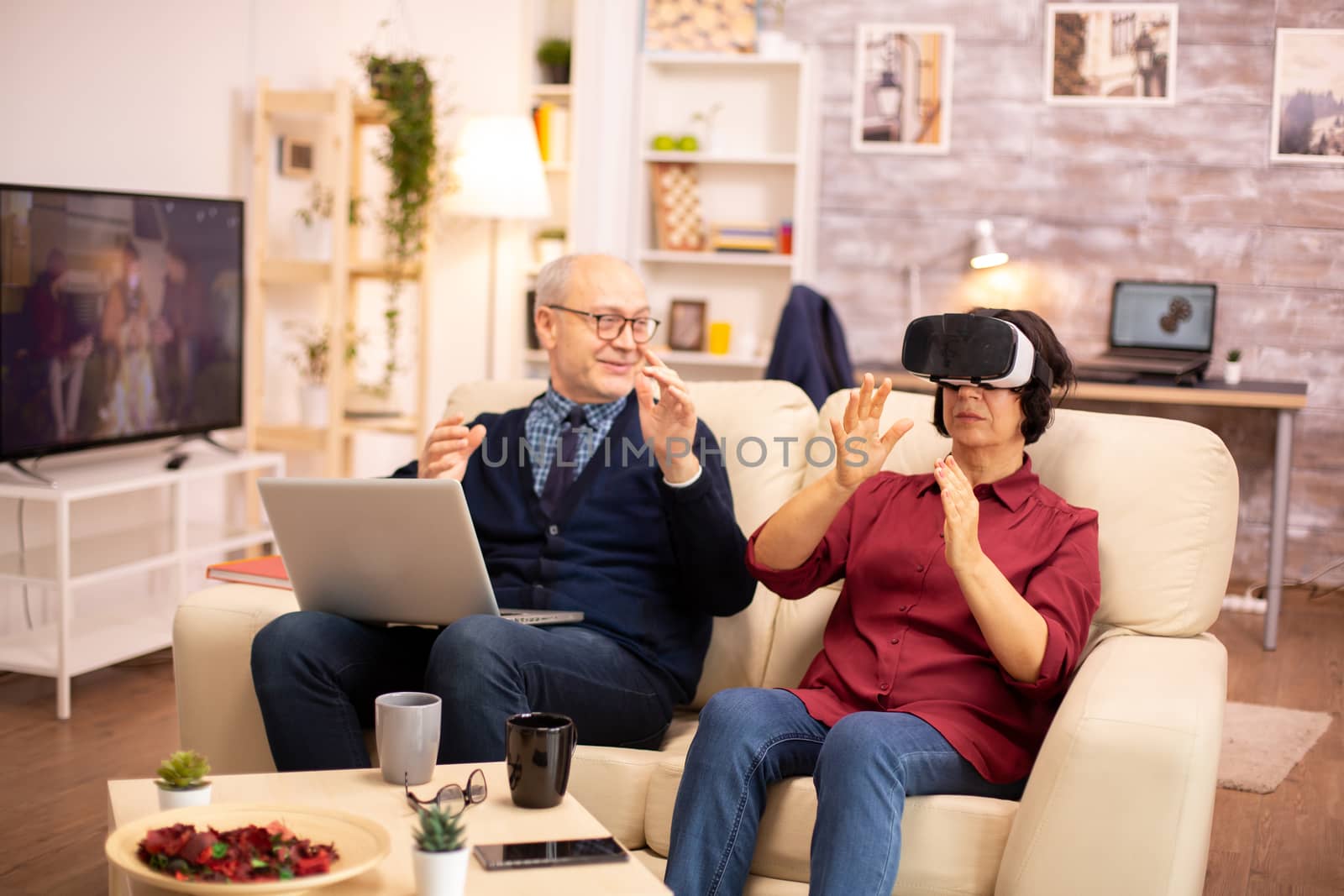 Old elderly retired woman in her 60s experiencing virtual reality for the first time in their cozy apartment