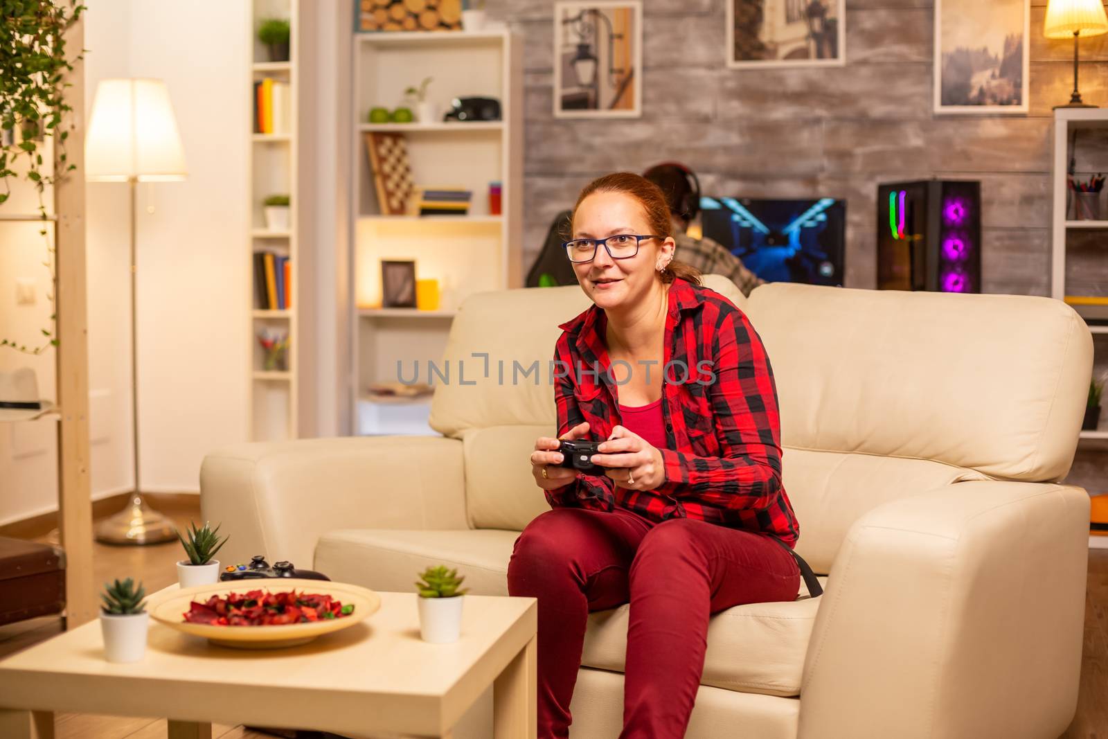 Woman gamer playing video games on the console in the living room late at night