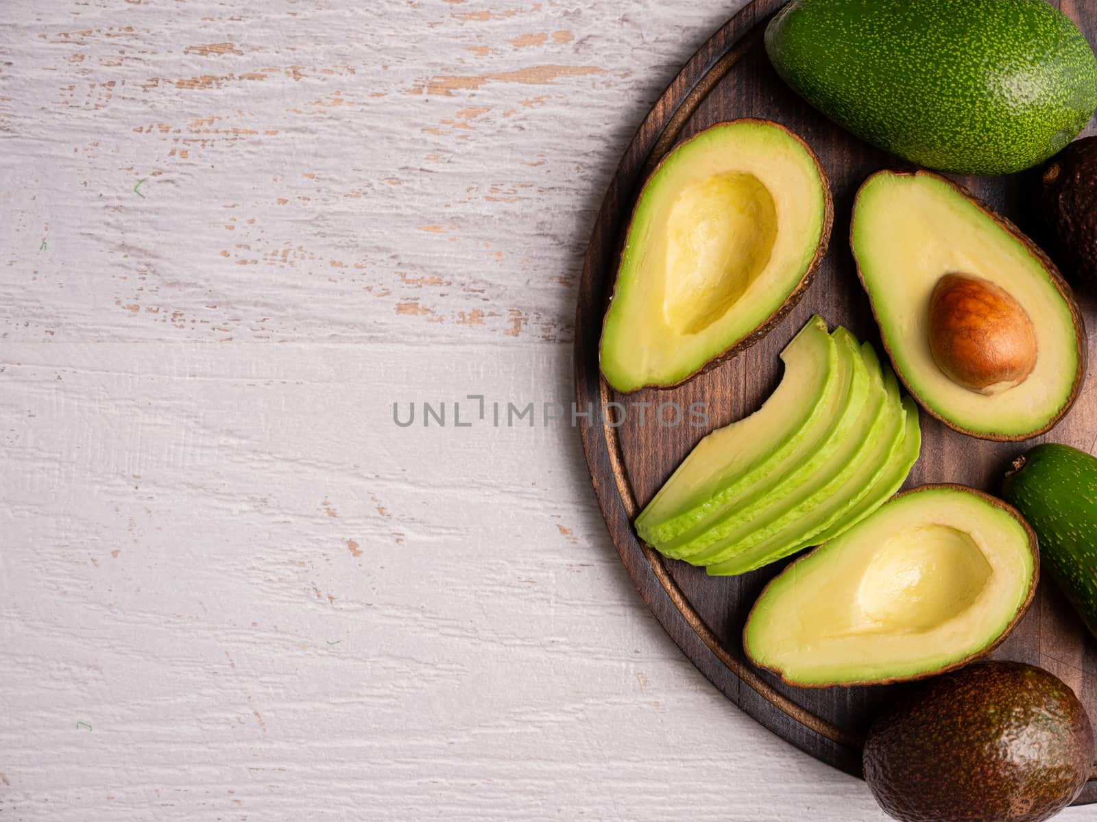 Top view of fresh cutted avocado on white wooden board.