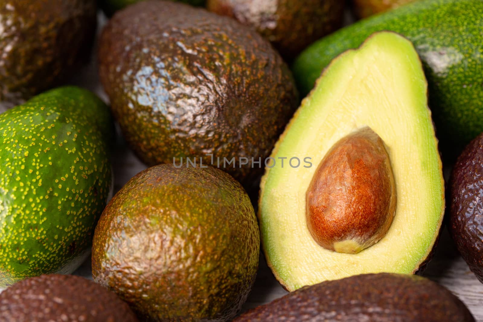 Cutted avocado fruit next to other one.