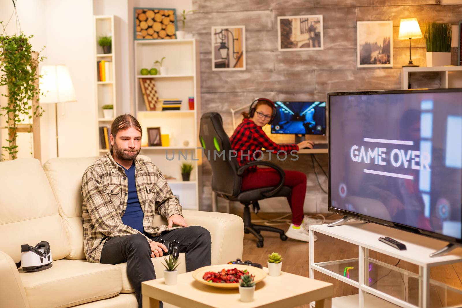 Stressed and angry male gamer losing a game while playing late at night in the living room