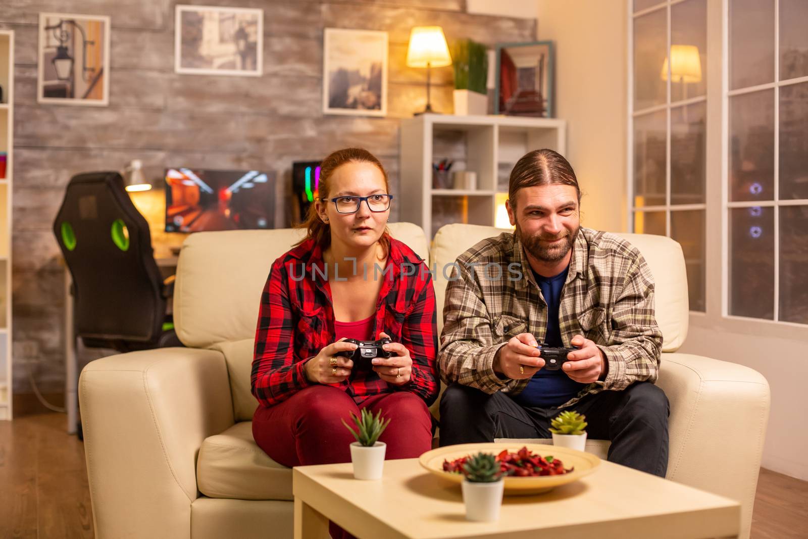 Gamers couple playing video games on the TV with wireless controllers in hands.