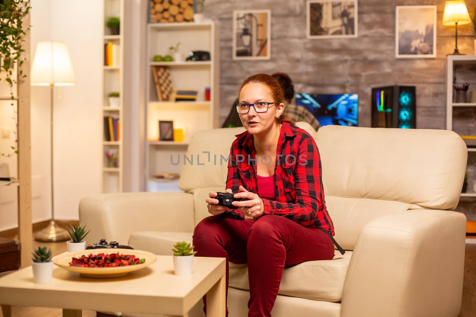 Woman gamer playing video games on the console in the living room late at night