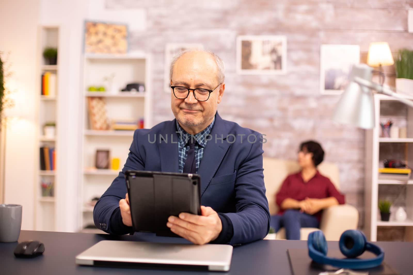 Senior man in his 60s using a modern digital tablet in his cozy home