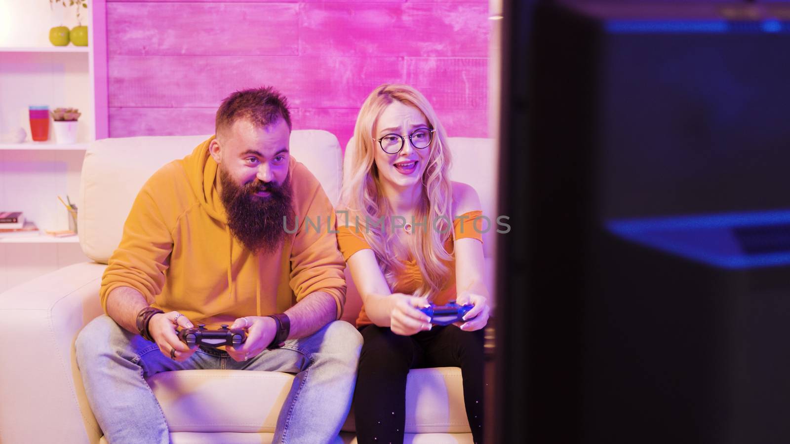 Upset young couple after losing while playing online video games using wireless controllers. Disappointment on their faces