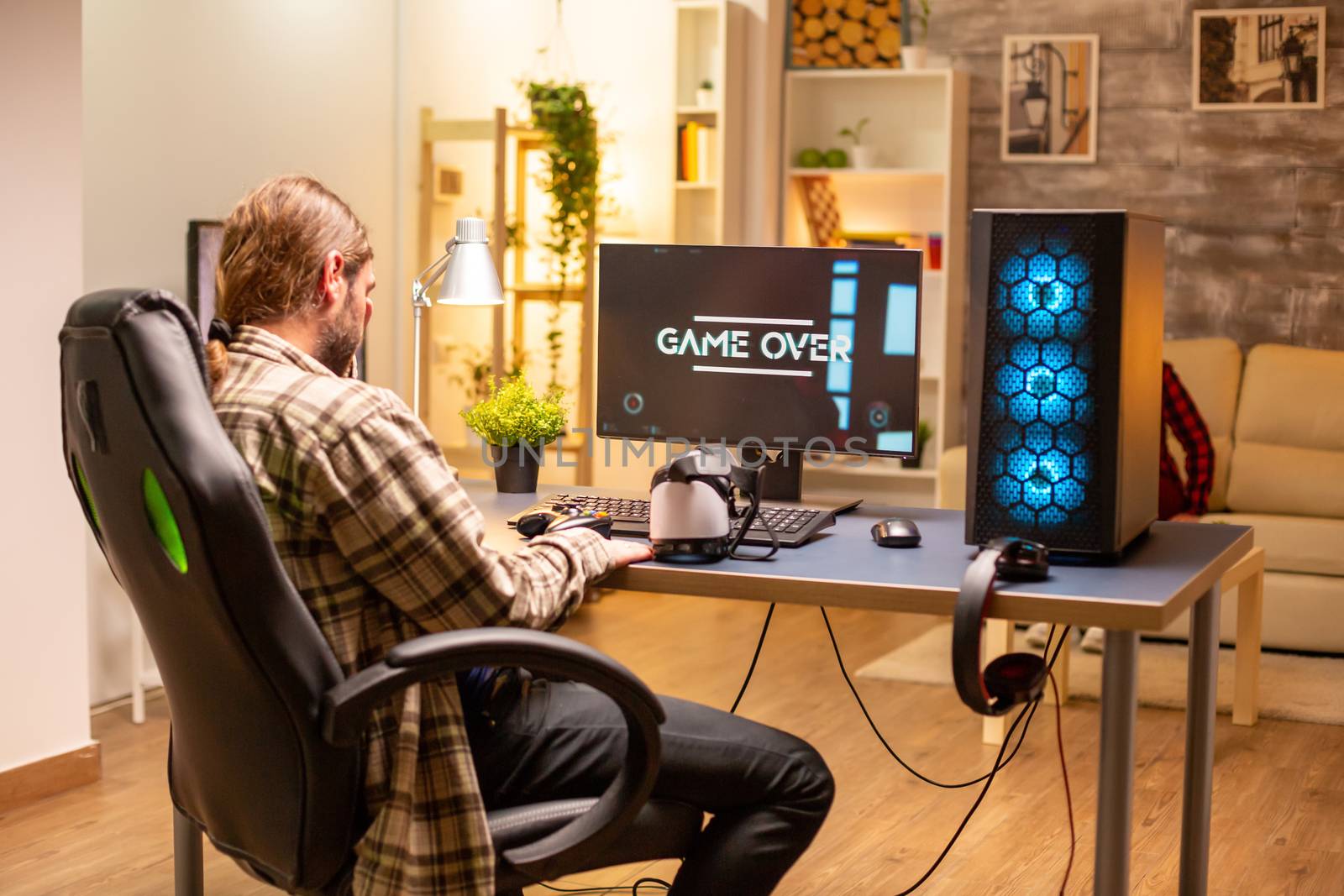 Man on his powerful PC computer in the living room late at night loosing a game.