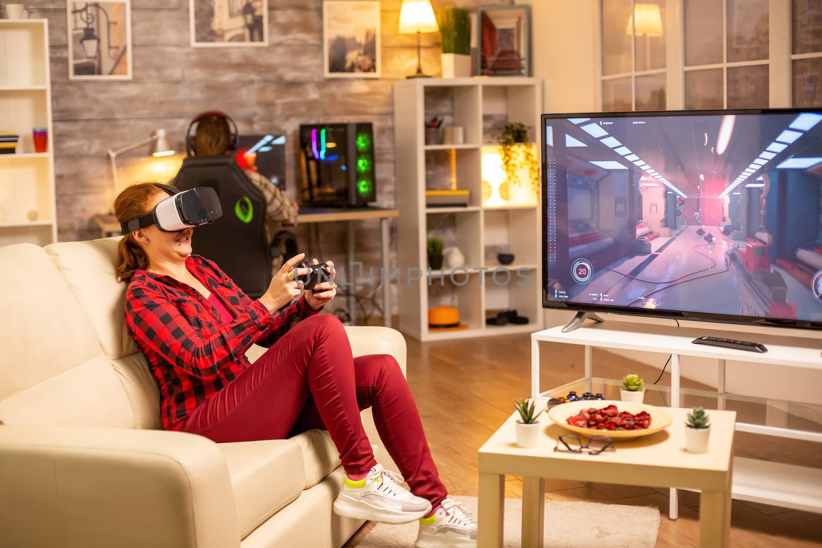 Woman gamer playing video games using a VR headset late at night in the living room