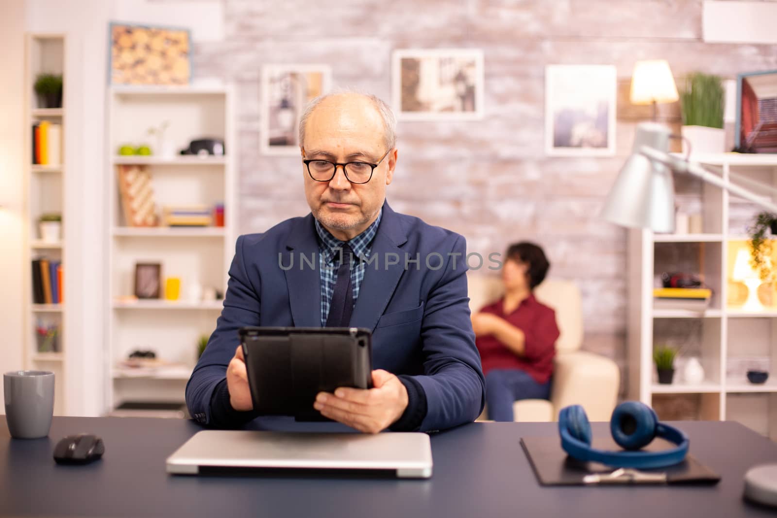 Senior man in his 60s using a modern digital tablet in his cozy home