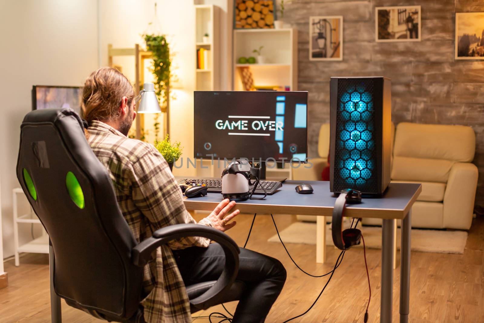 Man on his powerful PC computer in the living room late at night loosing a game.