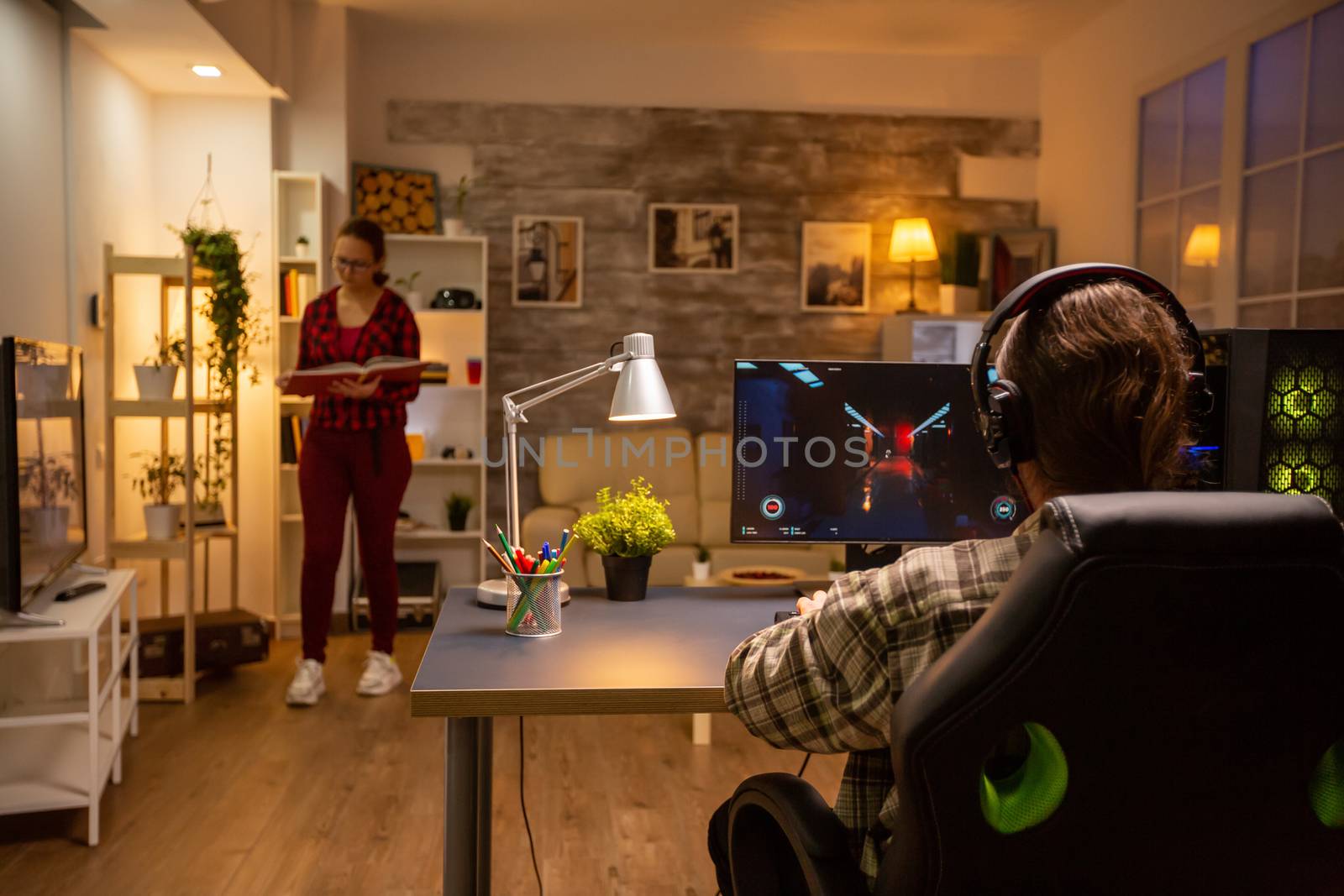 Back view of professional video gamer playing on powerful PC late at night in the living room.