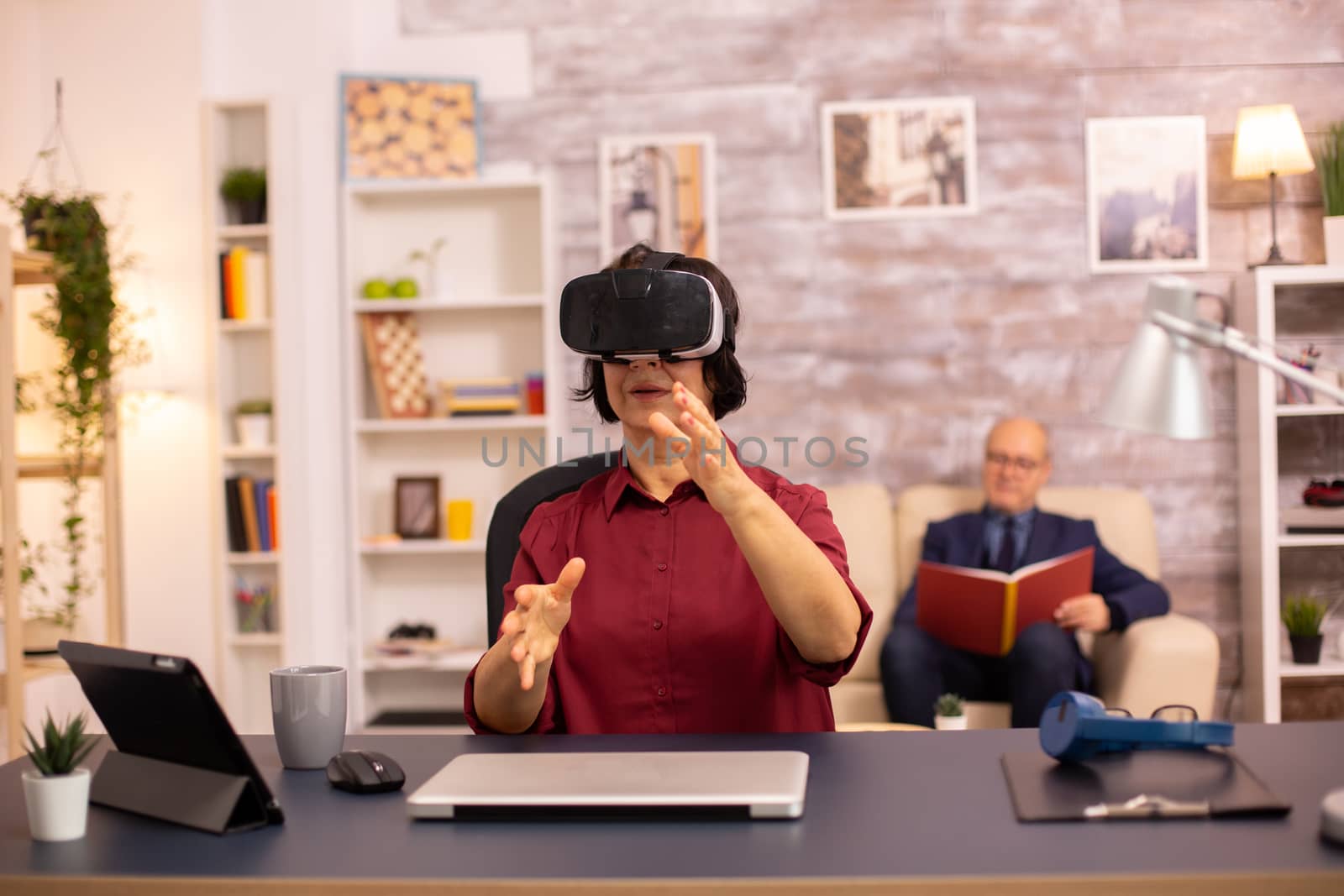 Old elderly woman using a VR virtual reality headset for the first time in her house. Concept of active elderly people using modern technology