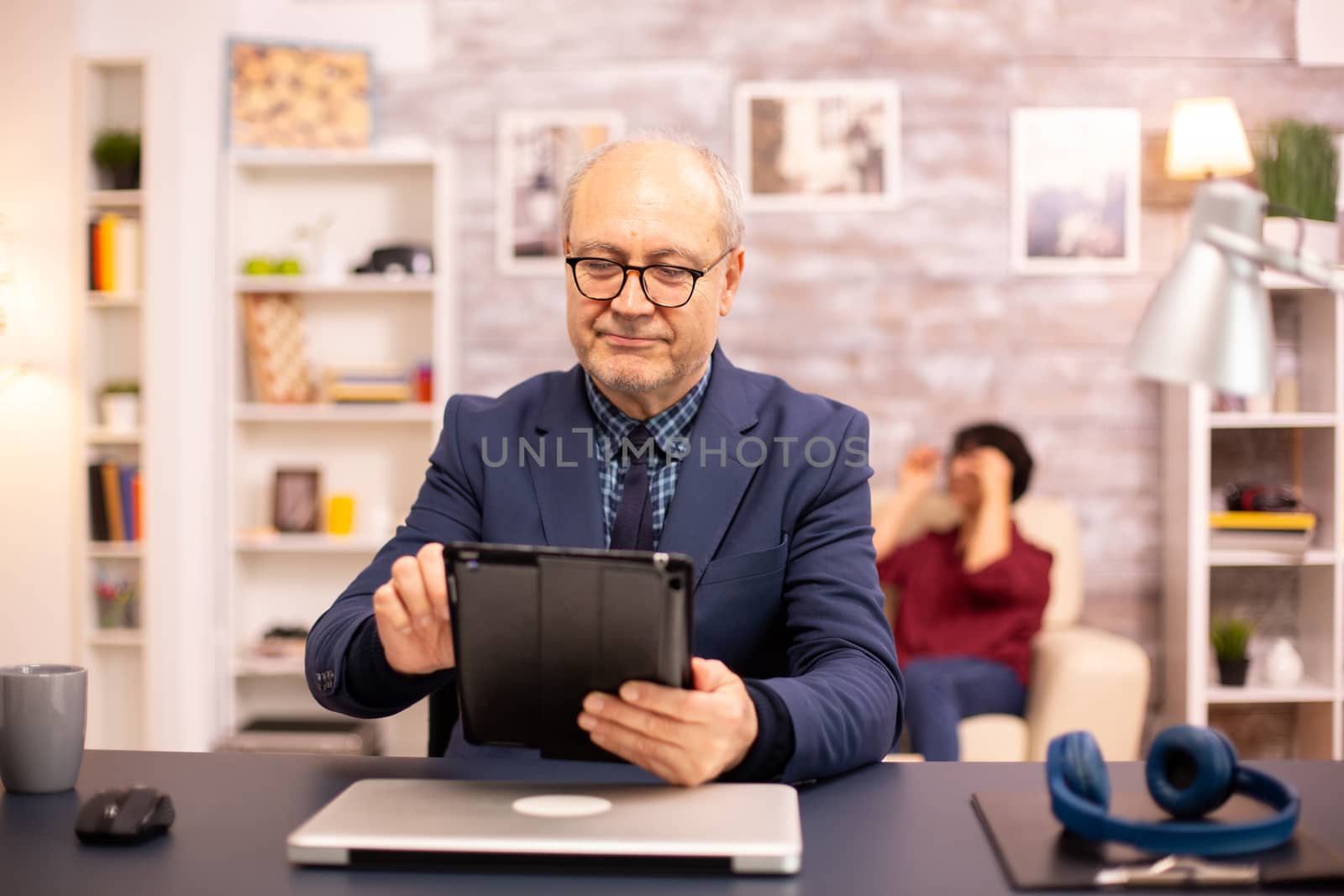 Senior man in his 60s using a modern digital tablet in his cozy home