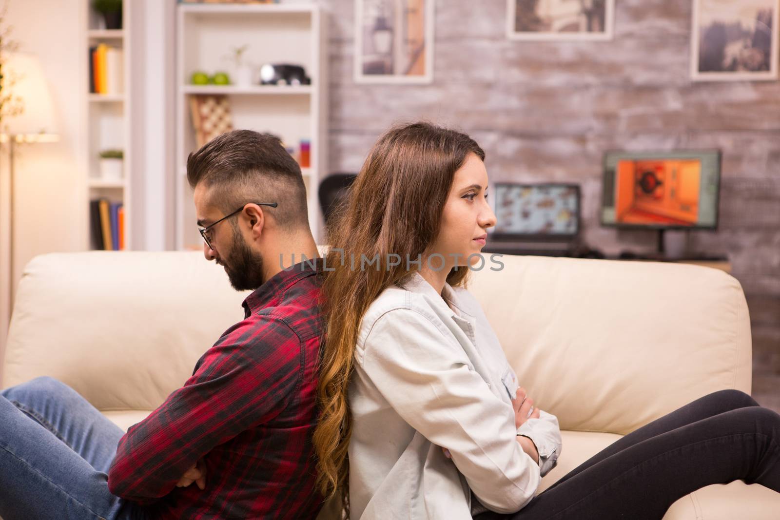 Couple sitting back to back on the couch ignoring each other. Relationship problems.