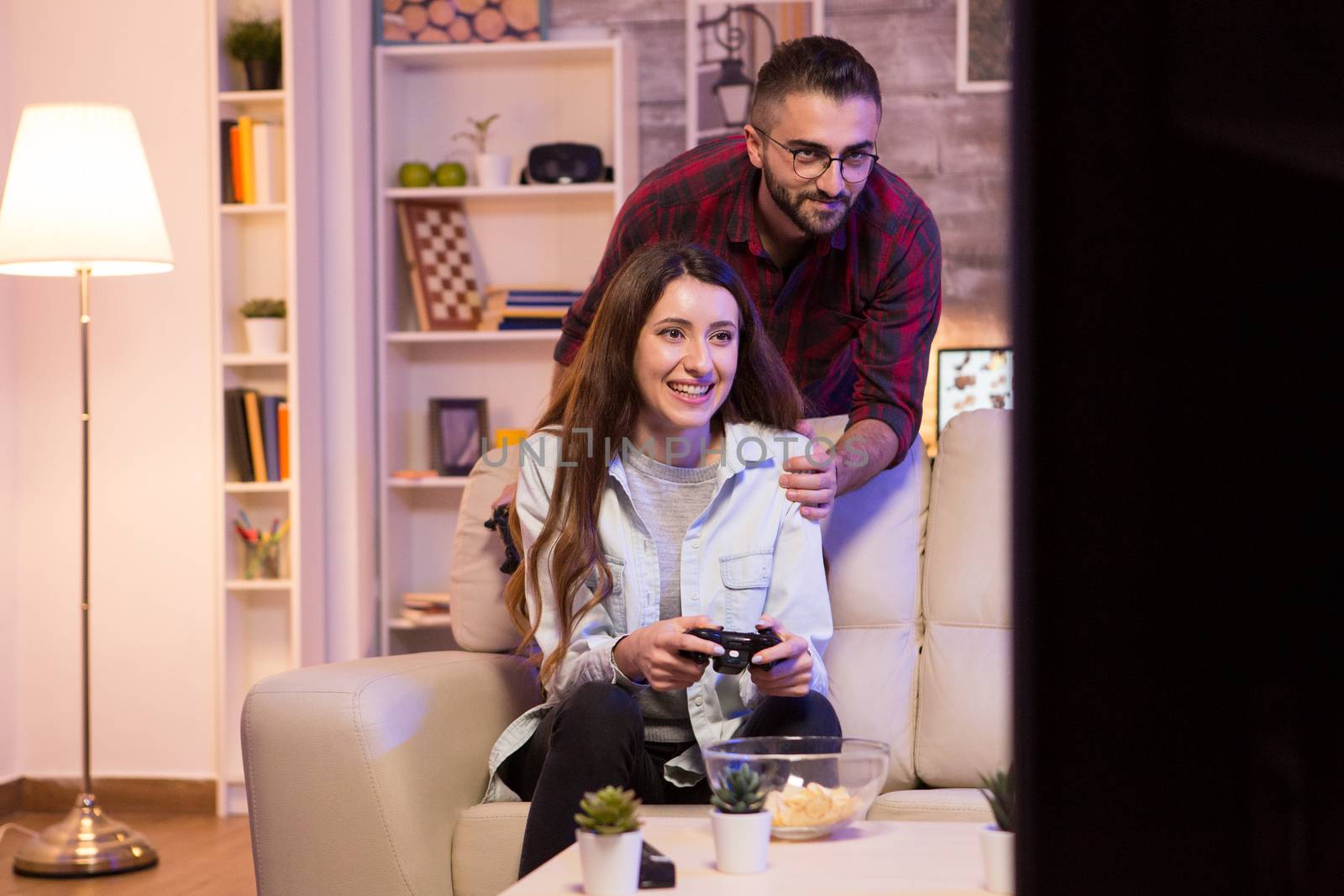 Photo of young couple playing video games on television at night.