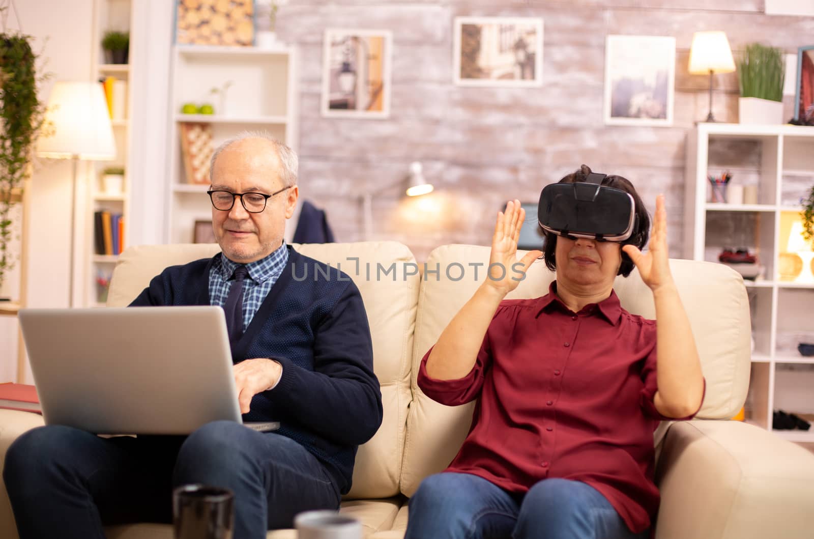 Old elderly retired woman in her 60s experiencing virtual reality for the first time in their cozy apartment
