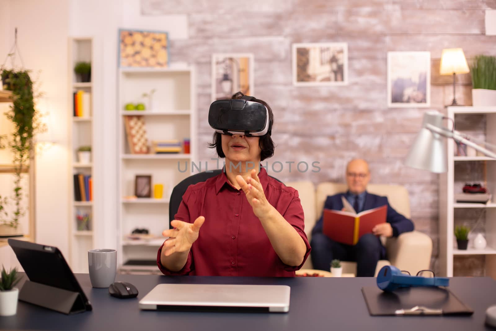 Old elderly woman using a VR virtual reality headset for the first time in her house. Concept of active elderly people using modern technology