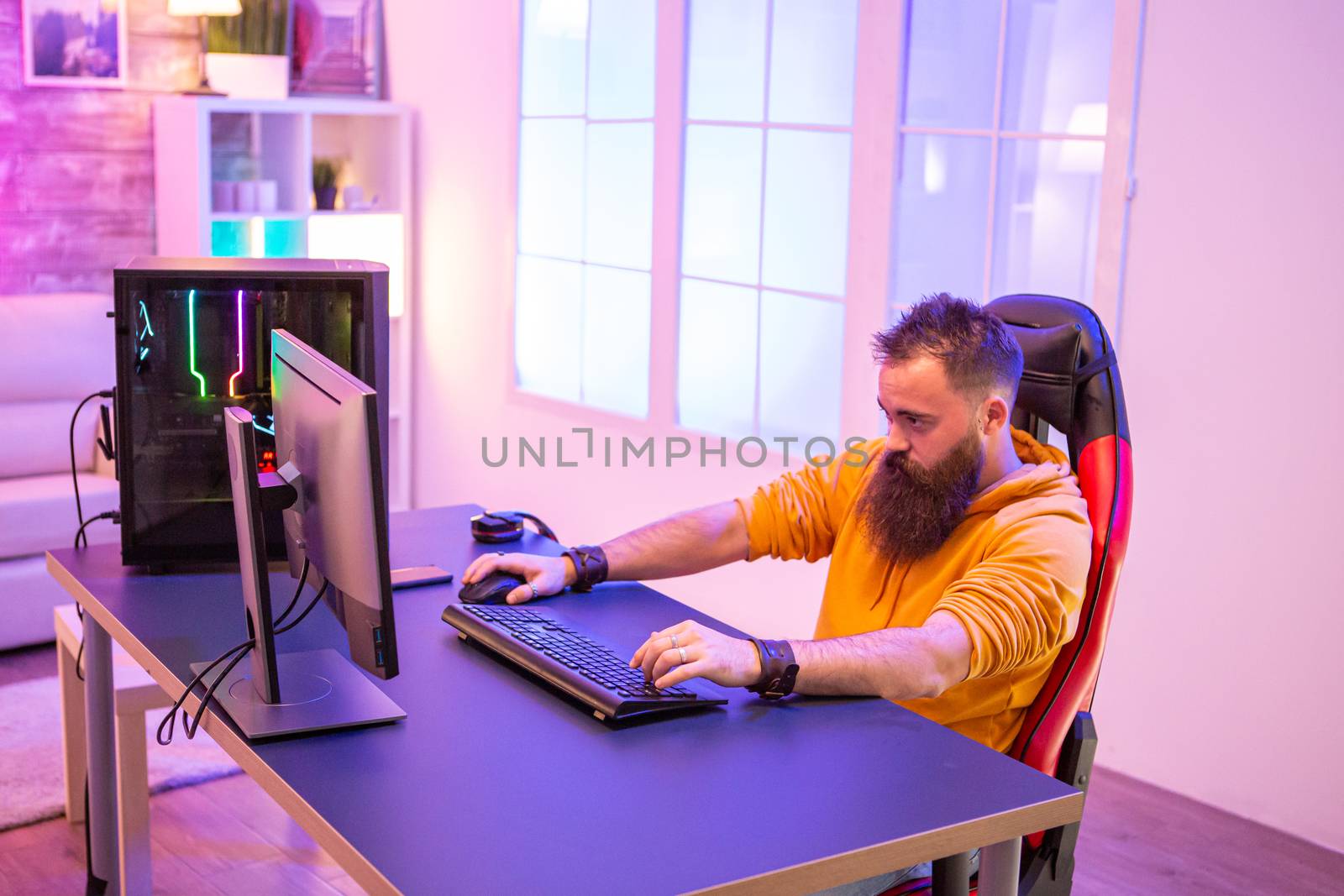 Professional gamer with long beard in front of powerful gaming rig by DCStudio