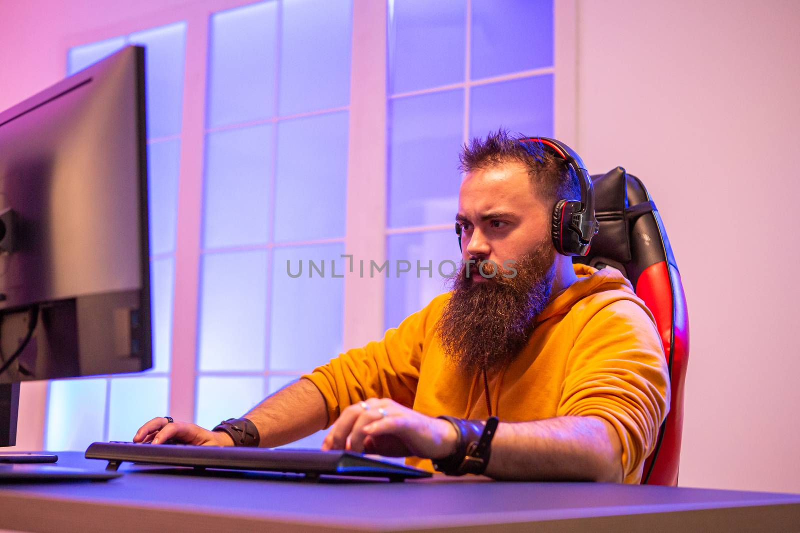 Professional gamer with long beard in front of powerful gaming rig by DCStudio
