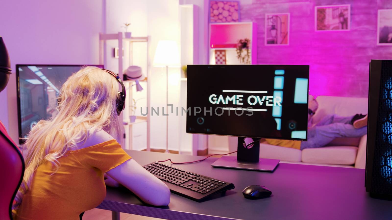 Sad blonde because she lost on a shooter game. Girl playing games and sitting on gaming chair.