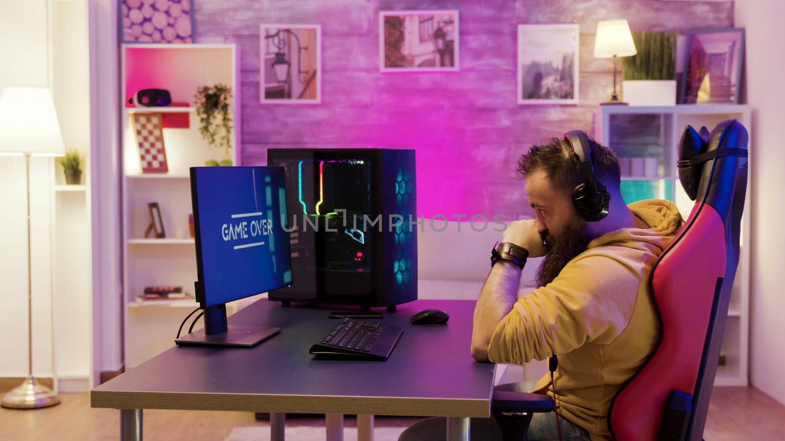 Upset professional game player after losing an important online game. Gamer playing in a room with colorful neon lights.