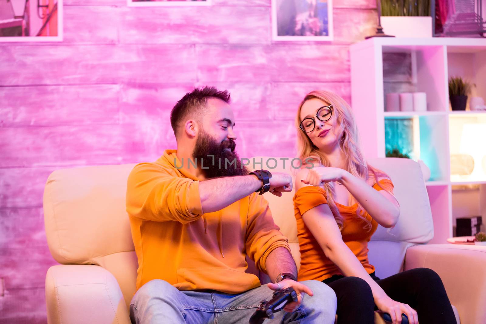 Young couple giving fist bump after playing online games by DCStudio