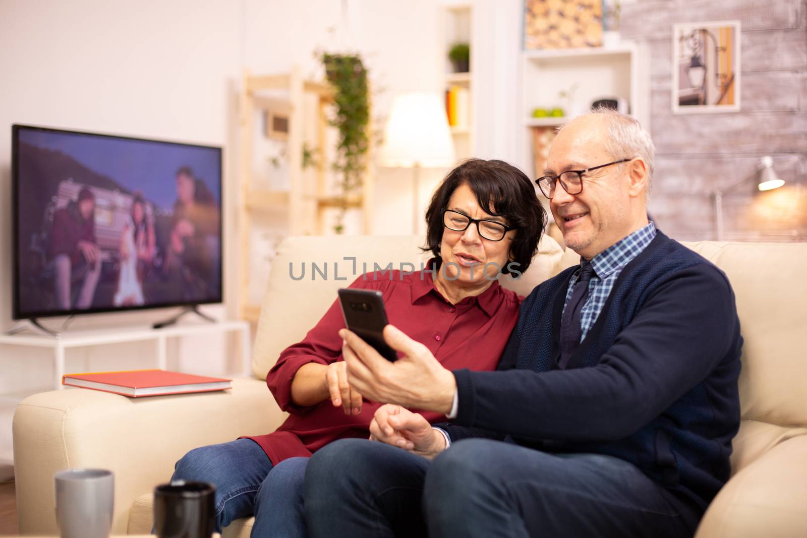 Old eldelry couple using a smartphone to talk with their family by DCStudio