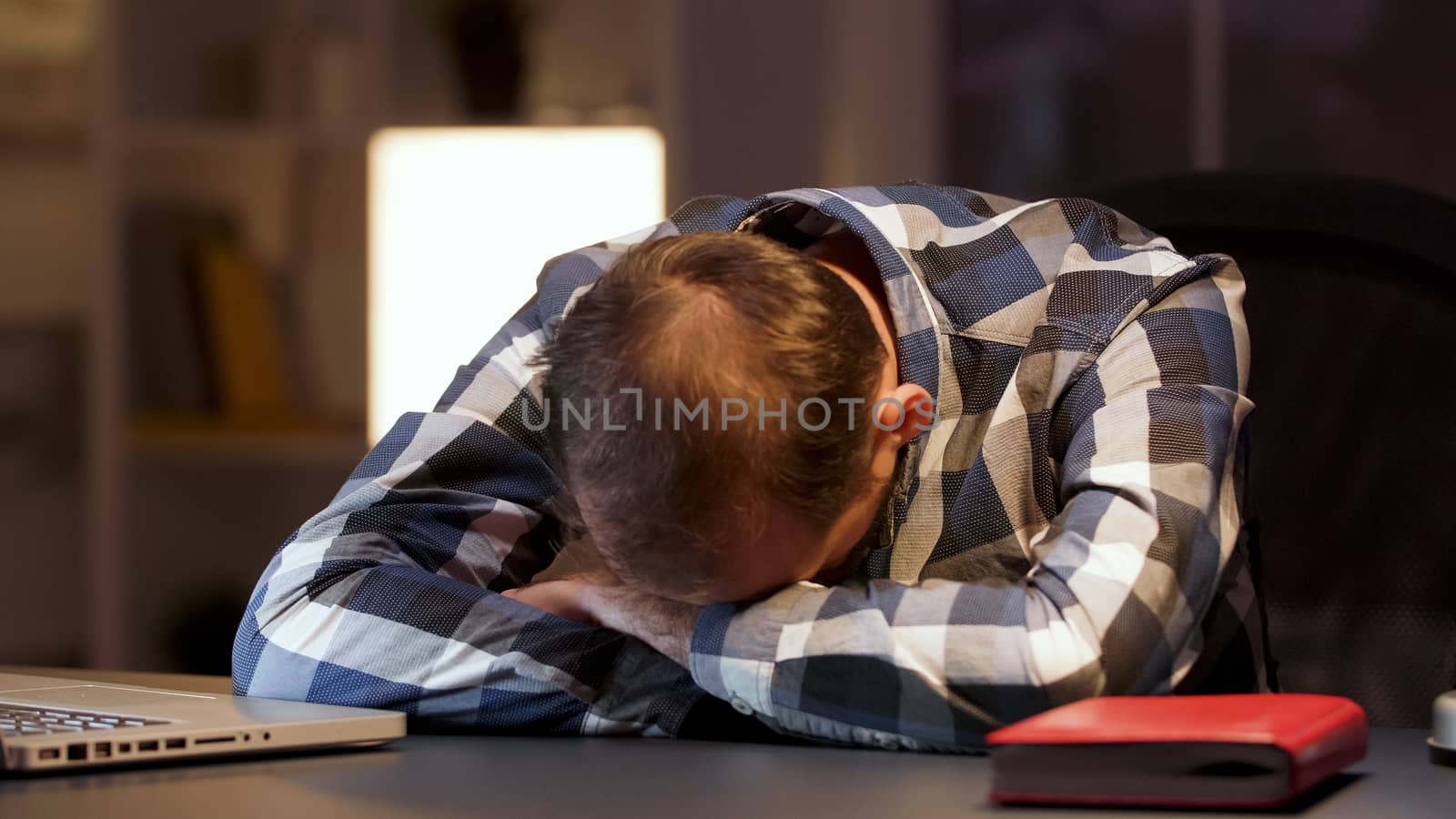 Tired businessman sleeping with head on desk in home office. Overworked entrepreneur.
