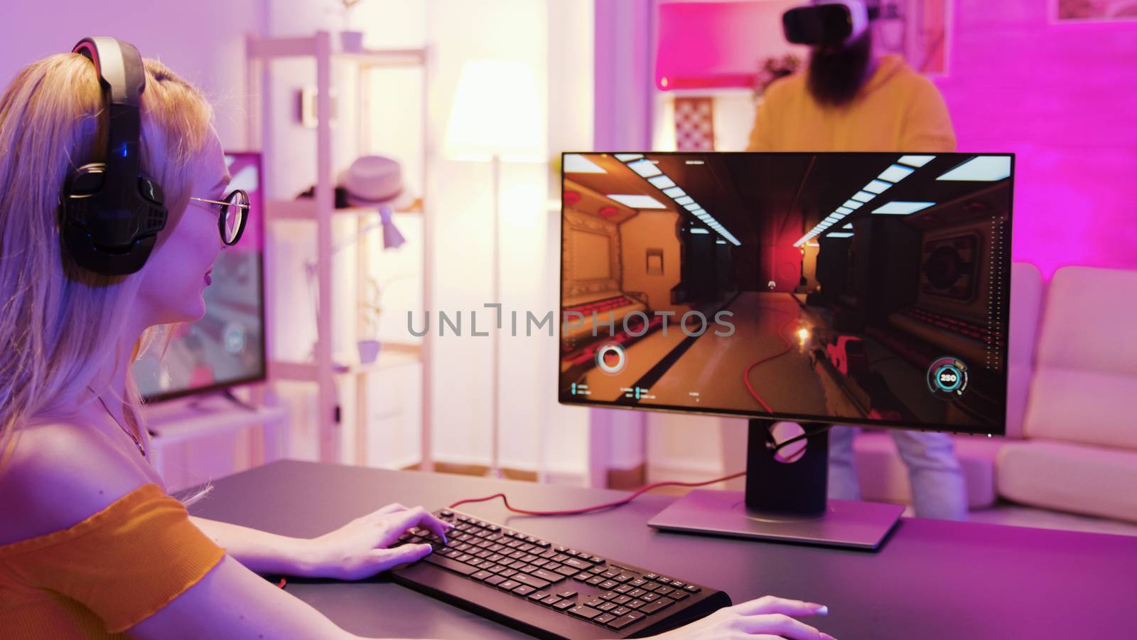 Girl playing shooter games in a room with colorful neon lights. Man with virtual reality headset.