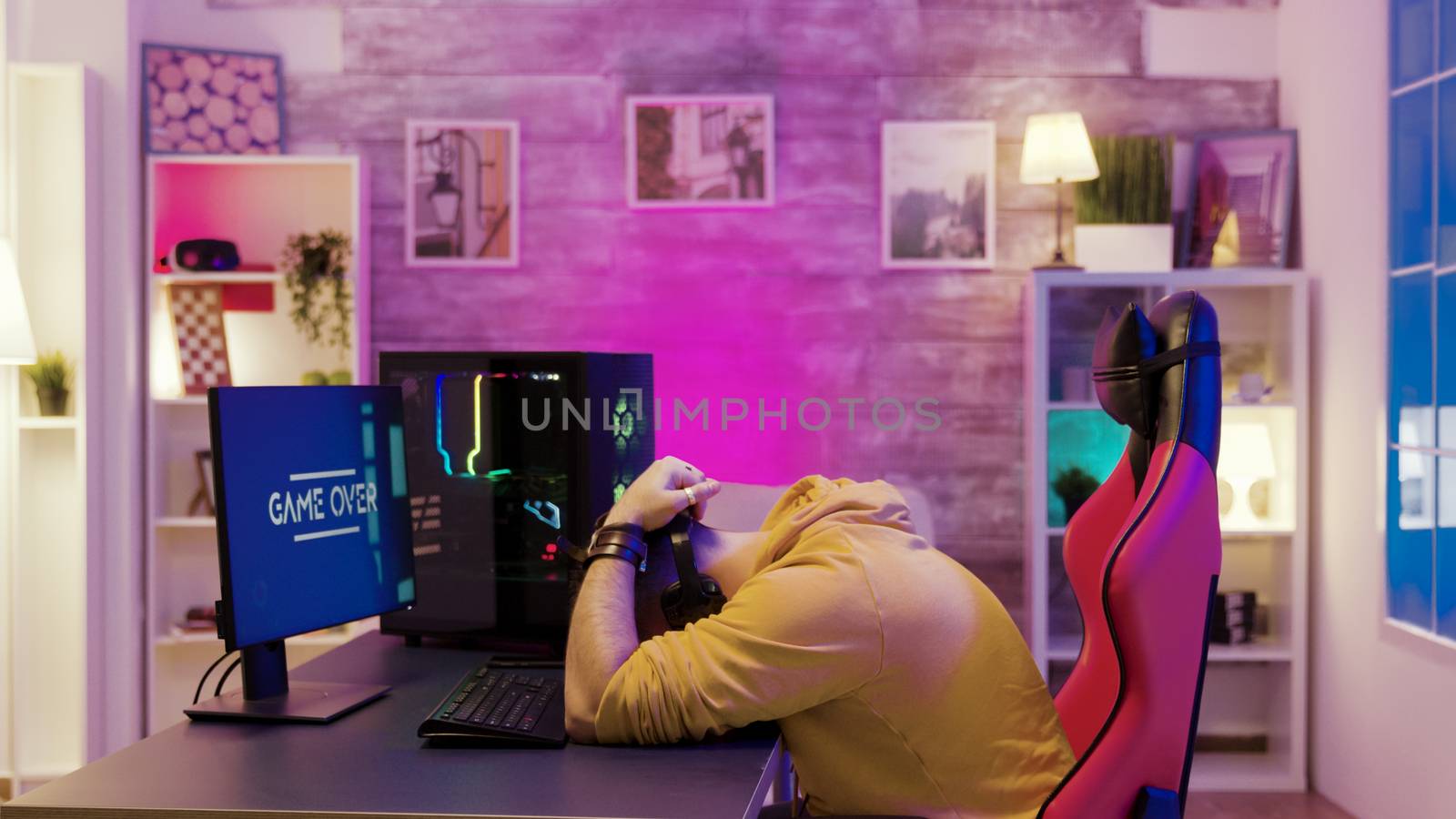 Successful man playing online video games on his computer. Professional game player in his room with neon lights.