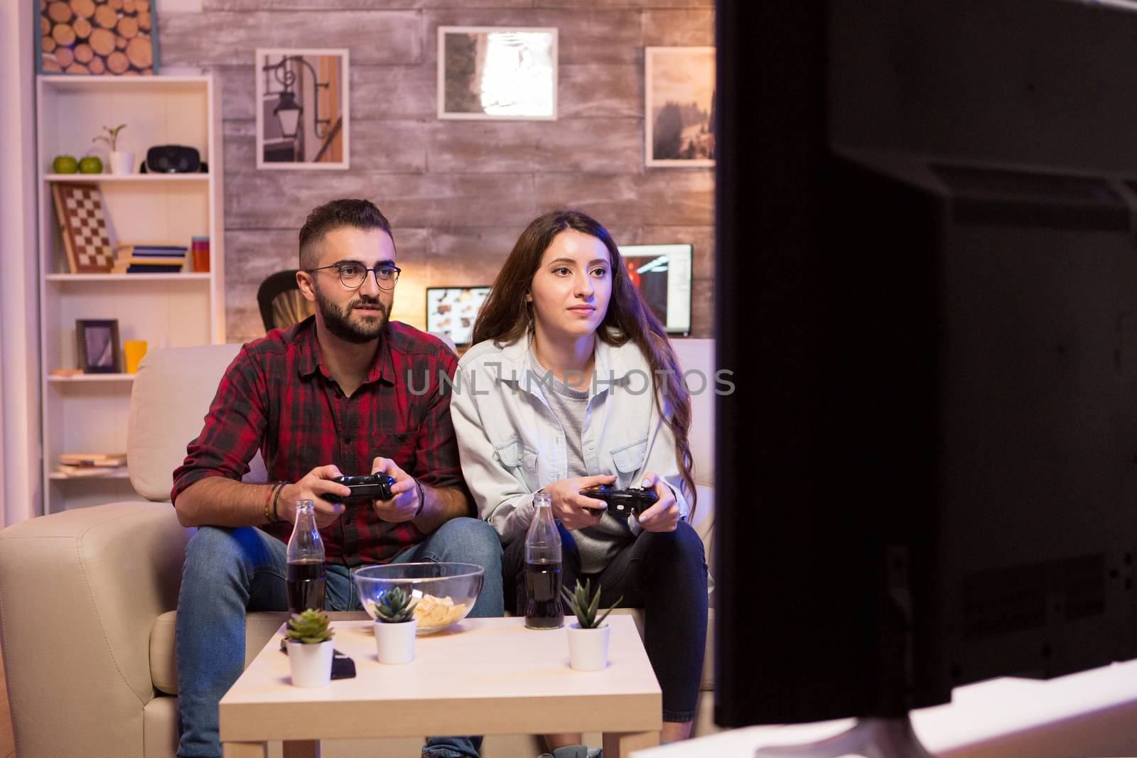 Boyfriend playing video games with his girlfriend on television using controllers.