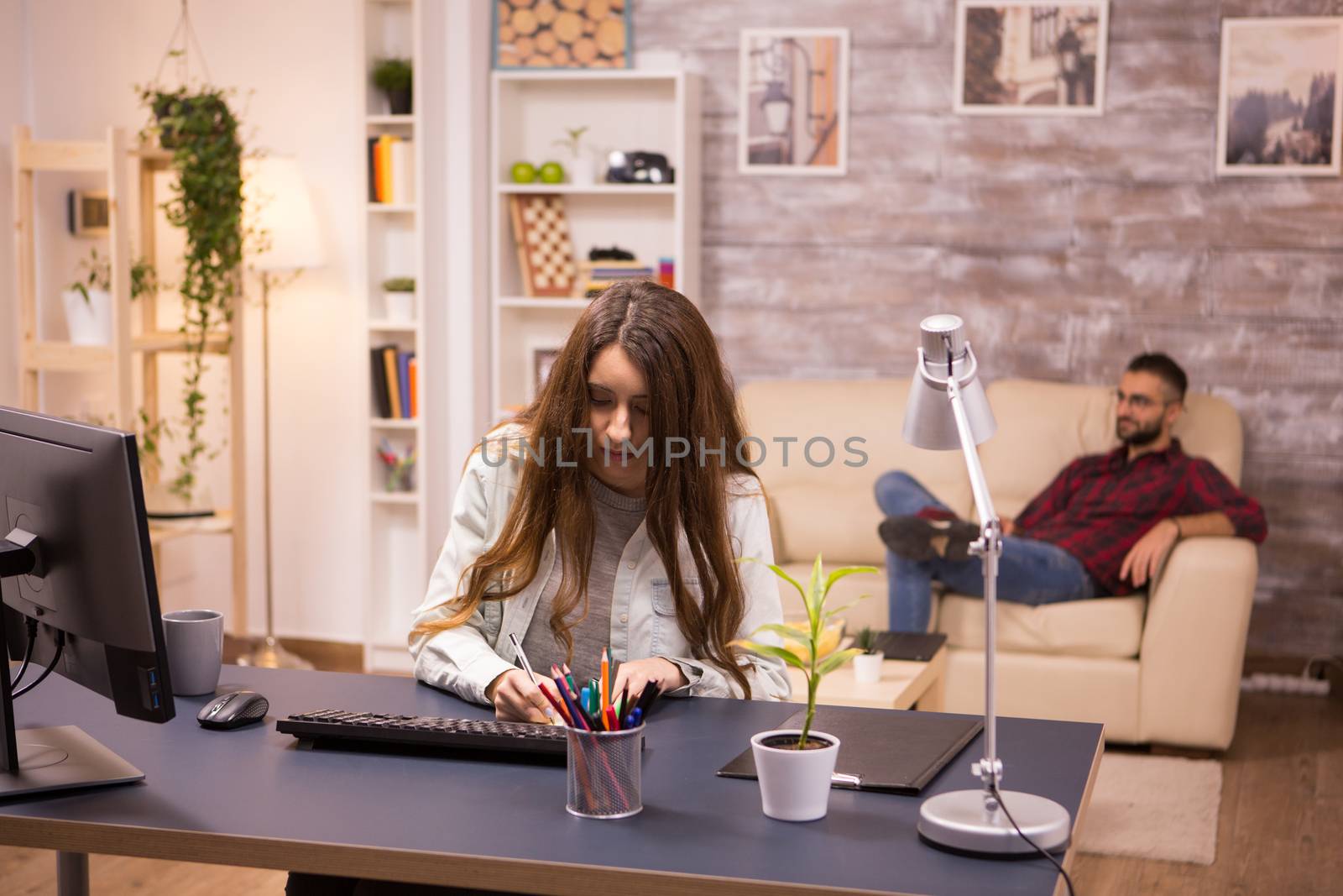 Female freelancer writing on sticky notes while working from home by DCStudio
