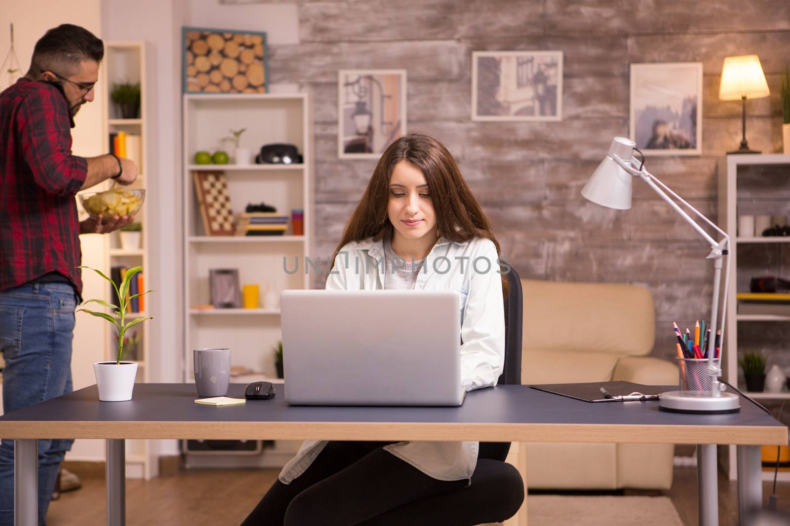 Girlfriend working on laptop in living room by DCStudio