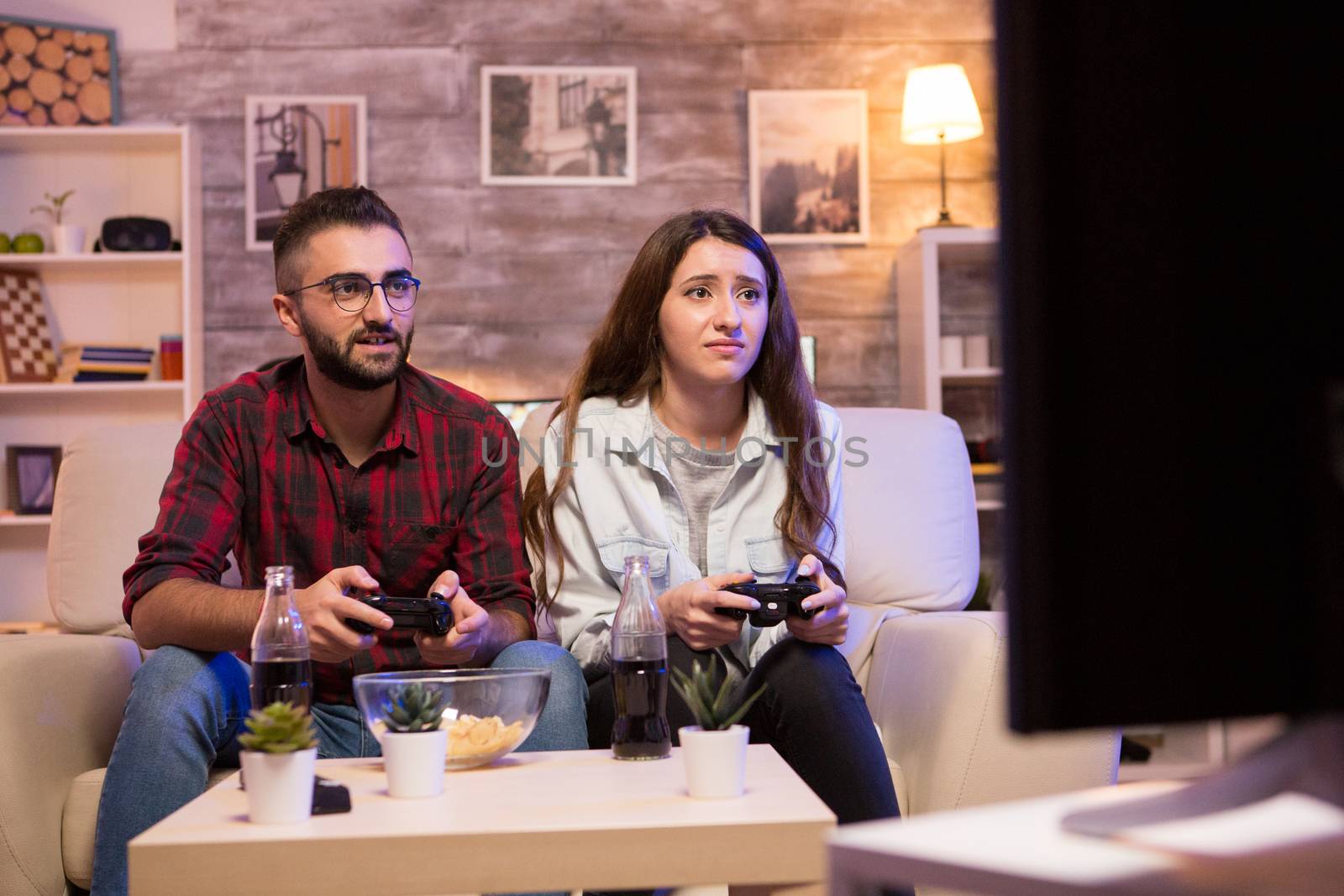Couple enjoying their time together while playing video games on television with controllers.