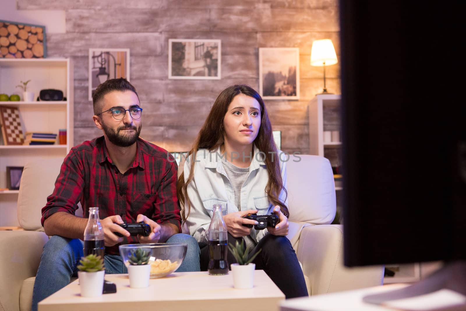 Couple playing video games on television at night. Couple using controllers.