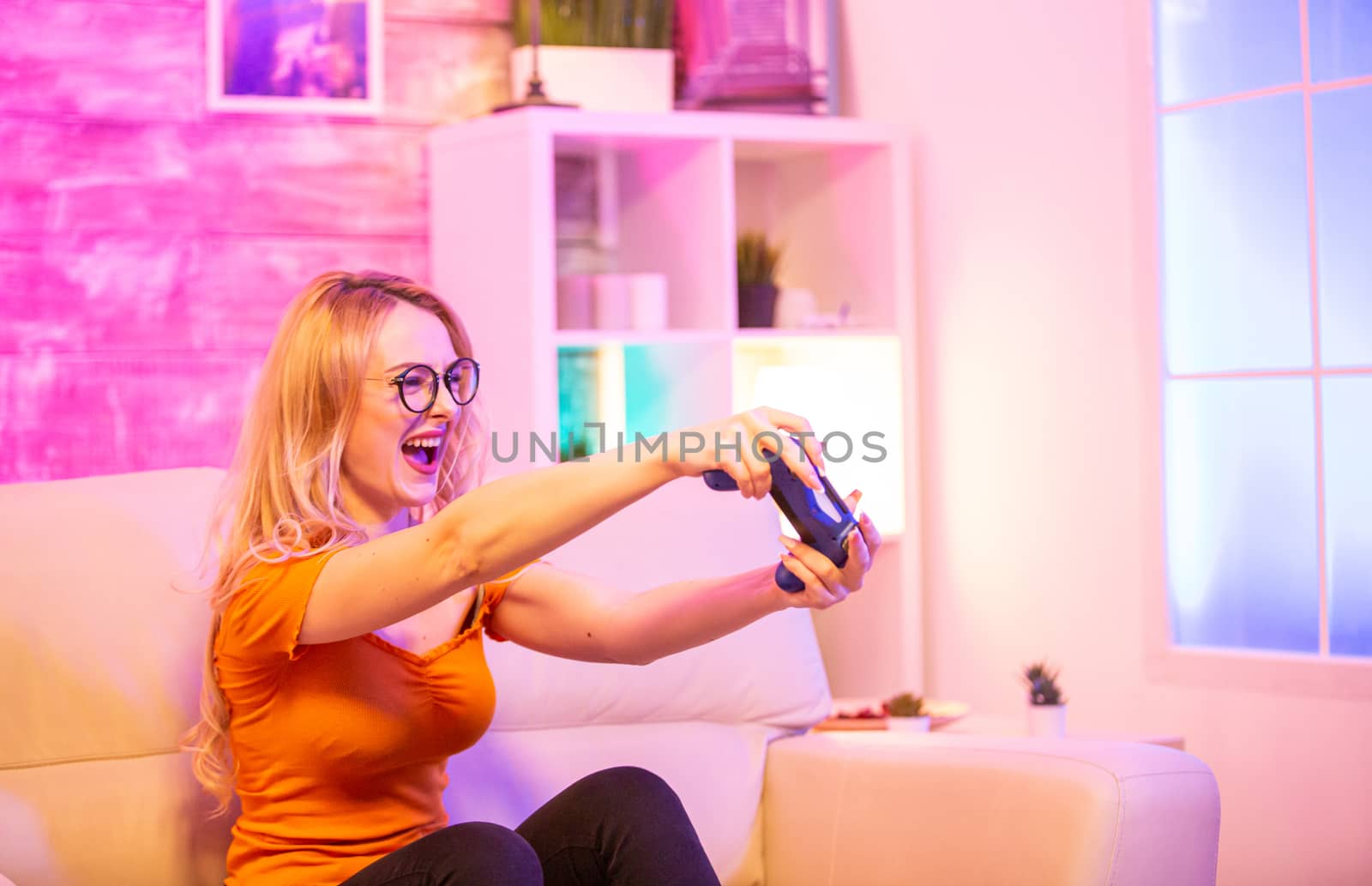 Beautiful blonde girl excited while playing video games using wireless controllers. Cheerful girl playing video games.