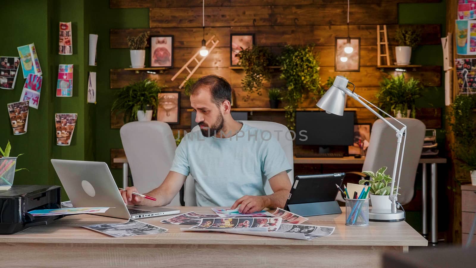 Young designer working on a laptop in a modern office by DCStudio