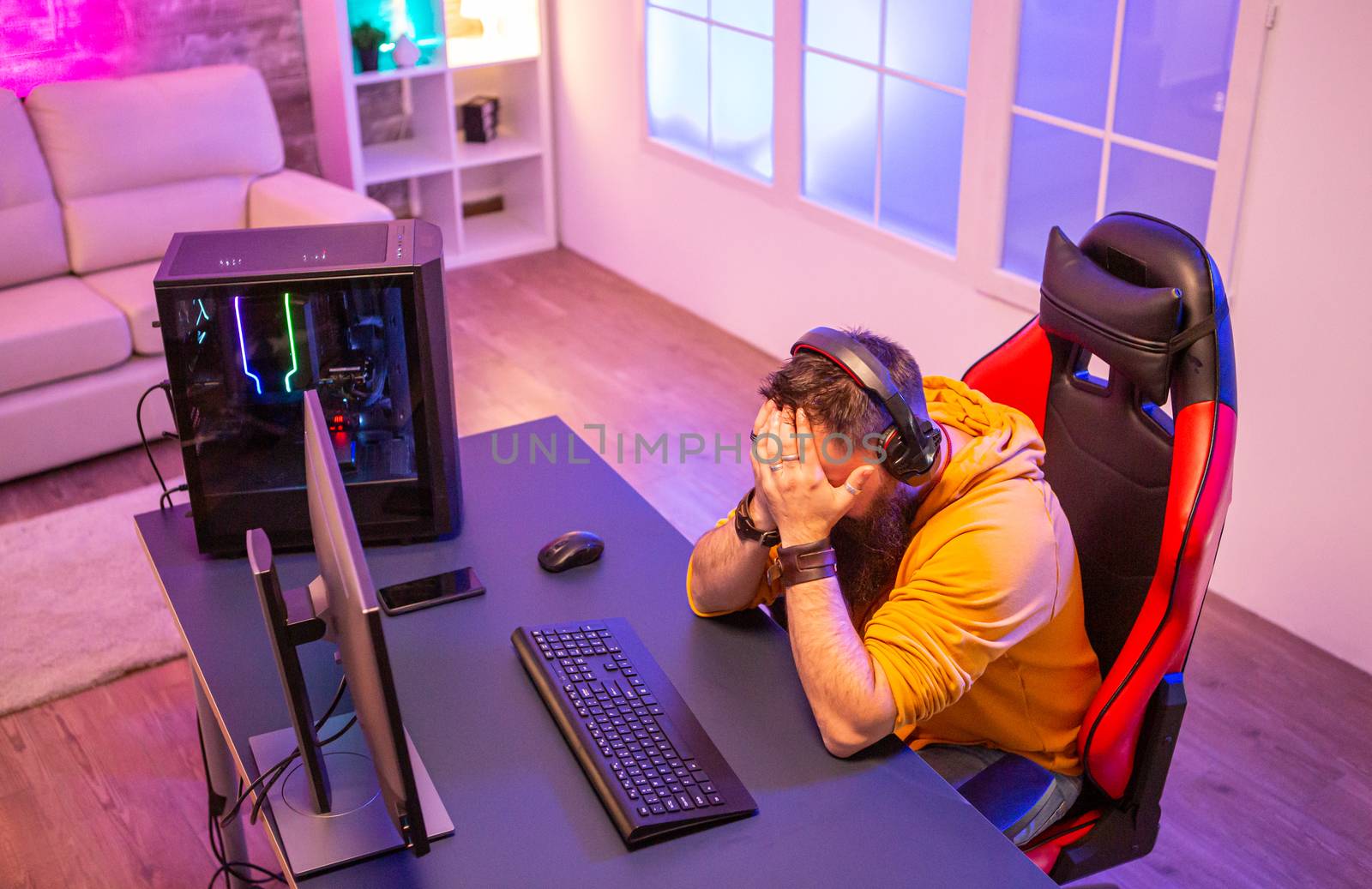 Upset professional gamer because he lost an important game. Room full of neon lights.