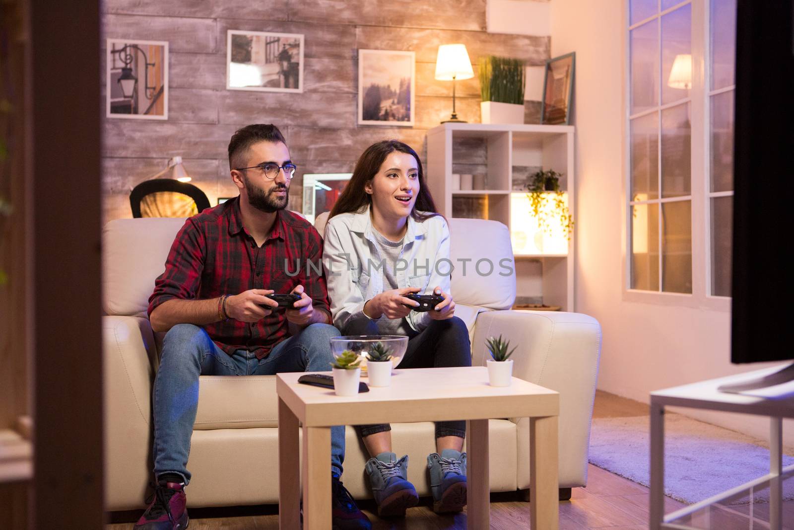 Young couple having a good time while playing video games on television by DCStudio