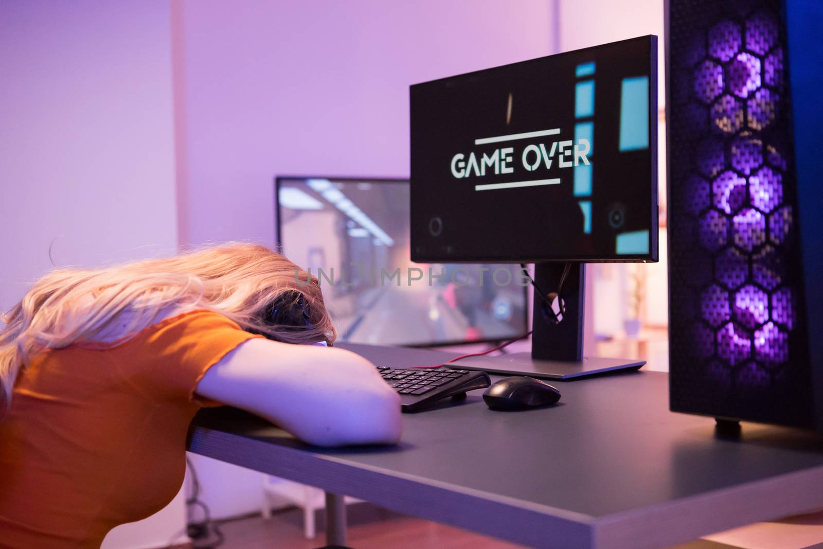 Girl keeping his head on desk office after she lost on computer game. Game over. Girl sitting on gaming chair.