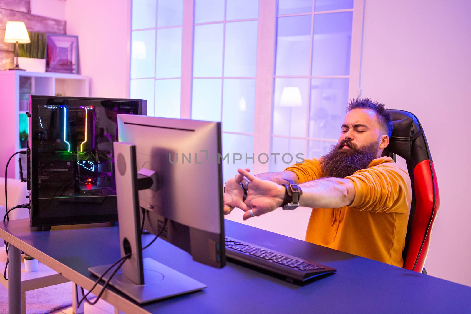 Professional gamer with long beard in front of powerful gaming rig by DCStudio