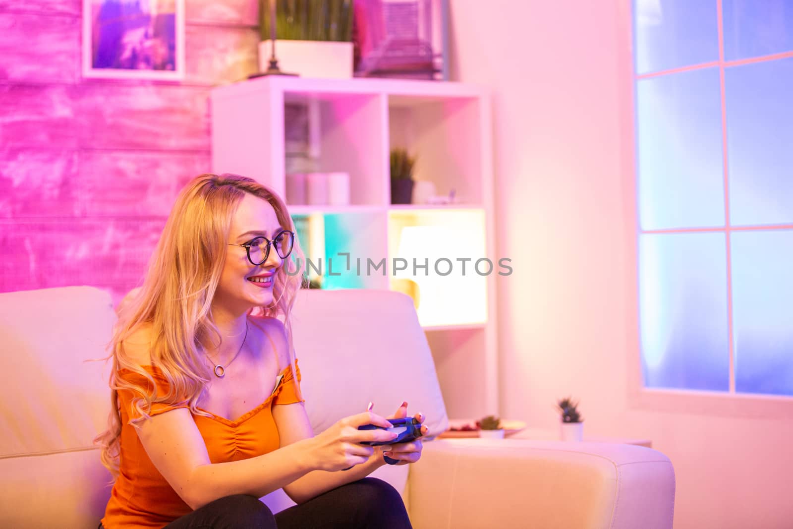 Beautiful blonde girl excited while playing video games using wireless controllers. Cheerful girl playing video games.