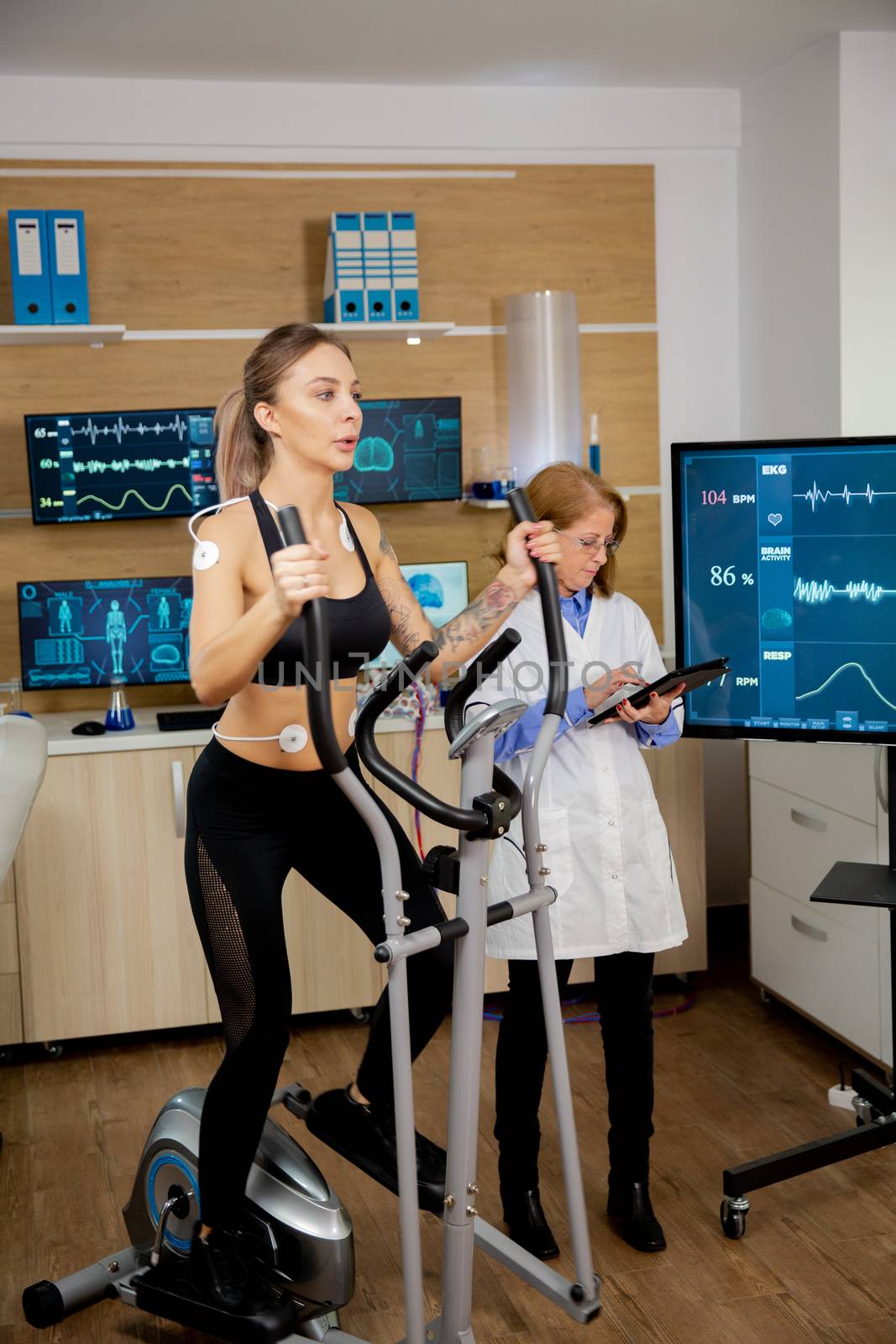Female athlete who runs tests on the stepper and has electrodes on it and the doctor follows on his tablet and screen his evolution by DCStudio