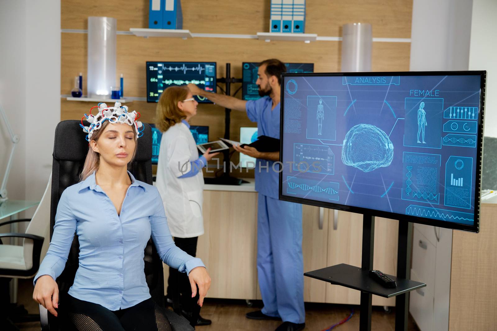 Patient who has a brain scan and his activity is seen on the big screen while doctors talk in the back. Studying the brain in the lab