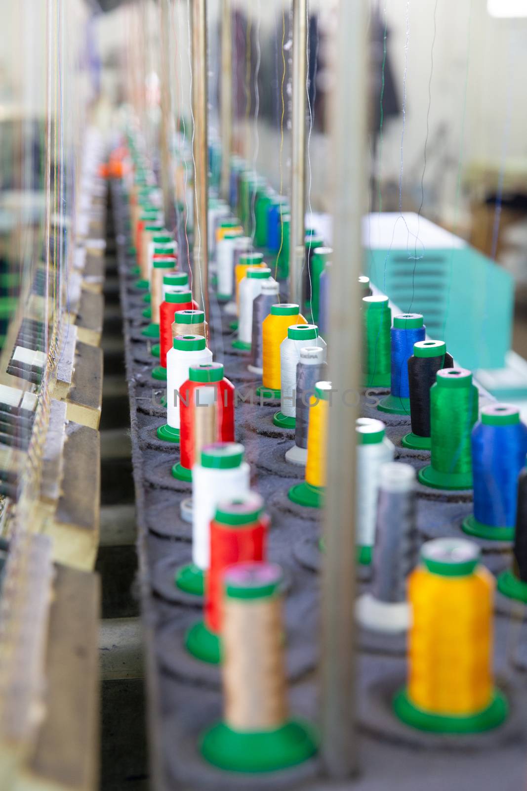 Close up with multicolored spools on an industrial sewing machine. Textile factory