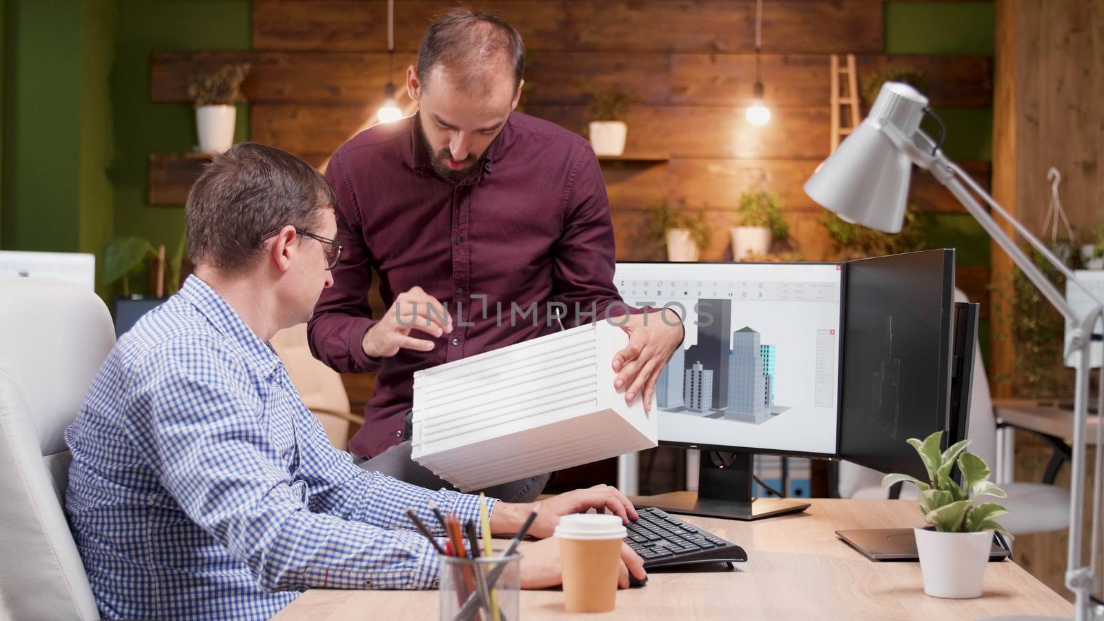 Architect in the office talking about the engineering for the new building structure with his assistant.